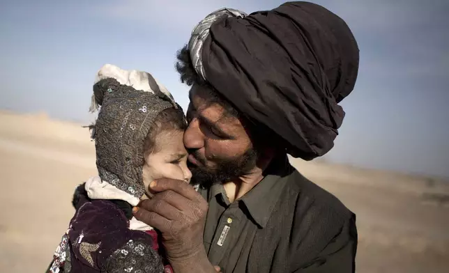 FILE - A nomad kisses his young daughter while watching his herd in Marjah, Helmand province, Afghanistan on Oct. 20, 2012. (AP Photo/Anja Niedringhaus, File)