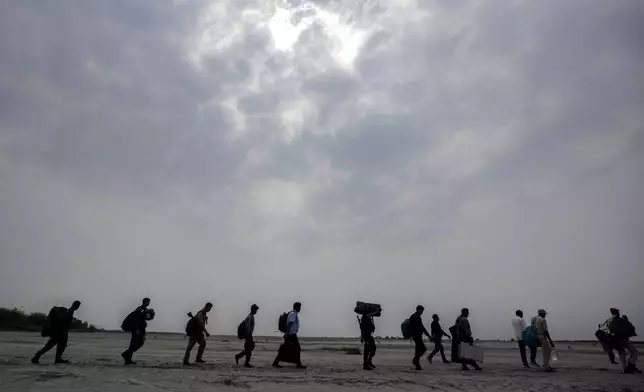 Polling officials carry Electronic Voting Machines (EVMs) across a dried riverbed of Brahmaputra on the eve of the national election at Baghmora Chapori (small island) of Majuli, about 350km (218 miles) east of the state capital Guwahati, India, Thursday, April 18, 2024. (AP Photo/Anupam Nath)