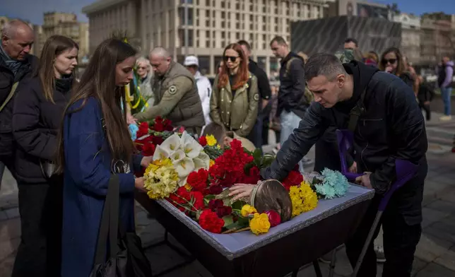 Oleksandr, right, a friend and fellow soldier bids farewell to fallen Ukrainian serviceman Vadym Popelniuk, born in 1991, after a religious service in Independence Square in Kyiv, Ukraine, Friday, April 5, 2024. (AP Photo/Vadim Ghirda)