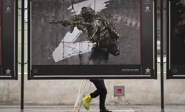 A man walks past a street exhibition of military posters named 'We bring Peace' dedicated to the military operation in Ukraine, in St. Petersburg, Russia, Friday, April 5, 2024. (AP Photo/Dmitri Lovetsky)
