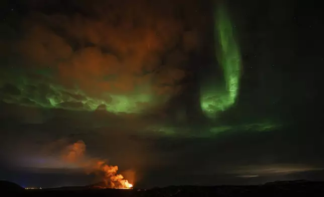 View of the eruption area with the northern lights dancing in the sky near the town of Grindavik, Iceland, Saturday April 6, 2024. (AP Photo/Marco di Marco)