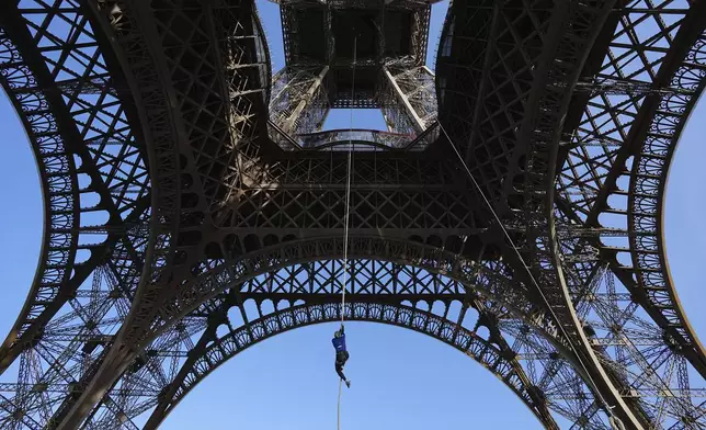 Anouk Garnier ascends by rope under the Eiffel Tower during an attempt to beat a record for climbing up a rope, Wednesday, April 10, 2024 in Paris. (AP Photo/Laurent Cipriani)