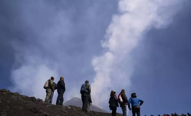 People look at volcanic vortex rings emerging from a new pit crater on the north side of the southeast crater of the Etna Volcano in Sicily, Italy, Friday, April 5, 2024. (AP Photo/Giuseppe Di Stefano)