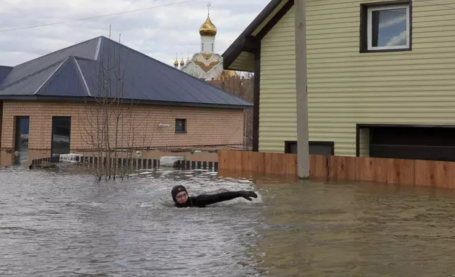 A local resident swims in the flooded street between houses in Orenburg, Russia, on Saturday, April 13, 2024. Over 11,700 houses remain flooded in the Orenburg region and some 10,700 people have already been evacuated from flooded areas. The deluge hit the region after a dam on the Ural River burst last week under surging waters. (AP Photo/Vitaly Smolnikov)
