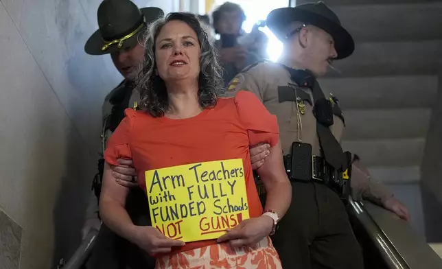 Allison Polidor, a gun control advocate, is escorted out of a legislative hearing room by state troopers, as families waited to testify in favor of gun control measures, in Nashville, Tenn., April 18, 2024. (AP Photo/George Walker IV)