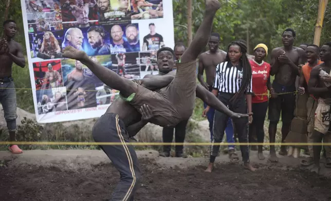 Amateur wrestlers tangle in what is known as Soft Ground Wrestling, in Kampala, Uganda March 20, 2024. The open-air training sessions, complete with an announcer and a referee, imitate the pro-wrestling contests the youth watch on television. (AP Photo/Patrick Onen)