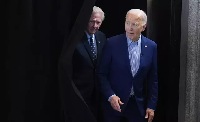 President Joe Biden, right, and United Steelworkers Union International President, David McCall, step out from behind a curtain to greet steelworkers at the United Steelworkers Headquarters, in Pittsburgh, Pa., April 17, 2024. (AP Photo/Alex Brandon)