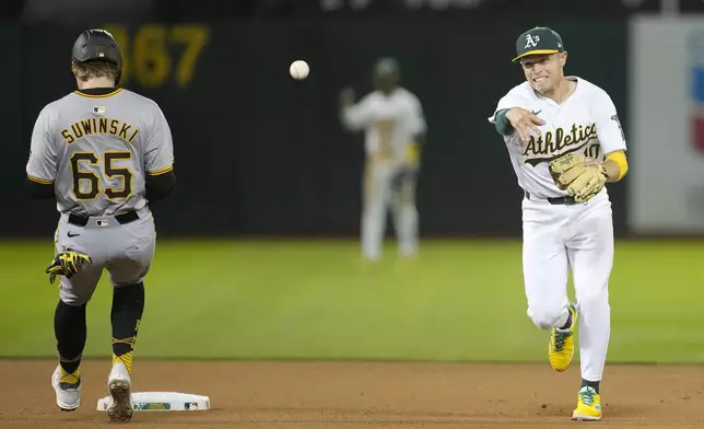Oakland Athletics shortstop Nick Allen, right, throws to first base after forcing Pittsburgh Pirates' Jack Suwinski (65) out at second base on a double play hit into by Jared Triolo during the seventh inning of a baseball game in Oakland, Calif., Monday, April 29, 2024. (AP Photo/Jeff Chiu)