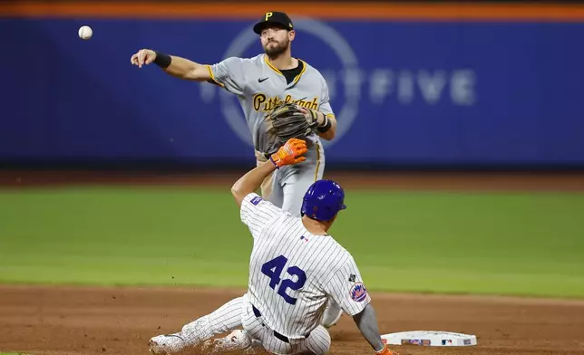 New York Mets' Tyrone Taylor, bottom, is out as Pittsburgh Pirates second baseman Jared Triolo, top, throws to first to complete a double play during the fifth inning of a baseball game, Monday, April 15, 2024, in New York. (AP Photo/Noah K. Murray)