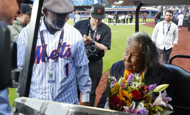 Former New York Mets Mookie Wilson, left, presents Rachel Robinson with flowers in honor of Jackie Robinson Day before a baseball game between the Mets and the Pittsburgh Pirates Monday, April 15, 2024, in New York. (AP Photo/Noah K. Murray)