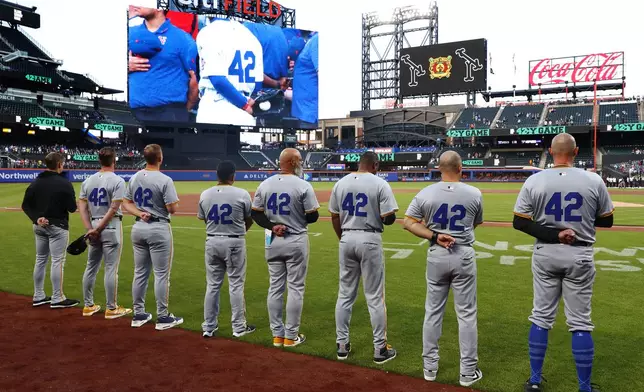 Pittsburgh Pirates stand on the third base line wearing number 42 in honor of Jackie Robinson Day before a baseball game against the New York Mets Monday, April 15, 2024, in New York. (AP Photo/Noah K. Murray)