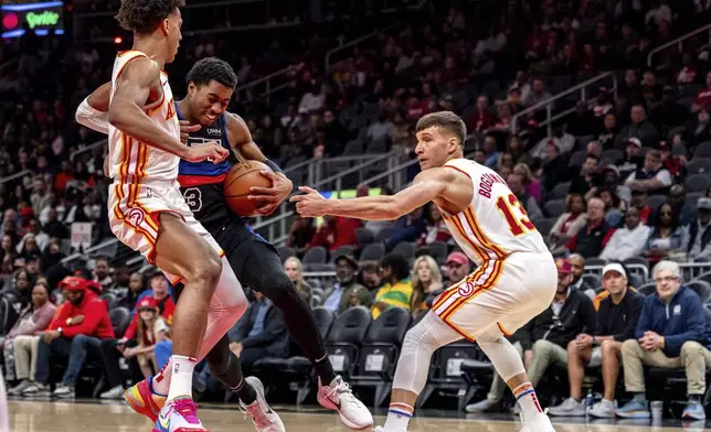 Detroit Pistons guard Jaden Ivey (23) goes to the basket against Atlanta Hawks forward Jalen Johnson (1) and Atlanta Hawks guard Bogdan Bogdanovic (13) during the first half of an NBA basketball game, Wednesday, April 3, 2024, in Atlanta. (AP Photo/Jason Allen)