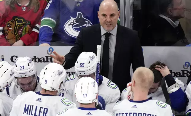 FILE - Vancouver Canucks head coach Rick Tocchet, top, talks to players during the third period of an NHL hockey game against the Chicago Blackhawks in Chicago, Sunday, Dec. 17, 2023. The Canucks won 4-3. In completing his first full season behind the Canucks bench, Tocchet is not alone among his coaching contemporaries in providing their respective teams a spark. Of the 16 teams entering the NHL playoffs this weekend, seven feature coaches who are in their first full year or hired as midseason replacements.(AP Photo/Nam Y. Huh)