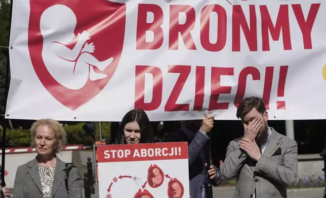 Anti-abortion activists hold a demonstration with a sign that says "We defend children" as the Polish parliament debates liberalizing the abortion law, in Warsaw, Poland, on Thursday April 11, 2024. The traditionally Catholic nation has one of the most restrictive laws in Europe — but the reality is that many women terminate pregnancies at home with pills mailed from abroad. (AP Photo/Czarek Sokolowski)