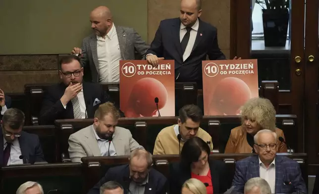 Dariusz Matecki, top right, a conservative lawmaker in the Polish parliament, displays a poster showing a fetus and the words "10th week after conception," during a vote on abortion in Warsaw, Poland, on Friday, April 12, 2024. Polish lawmakers voted Friday to continue work on four proposals that would loosen the law on abortion, a divisive issue in the traditionally Roman Catholic country which has a near-total ban. (AP Photo/Czarek Sokolowski)
