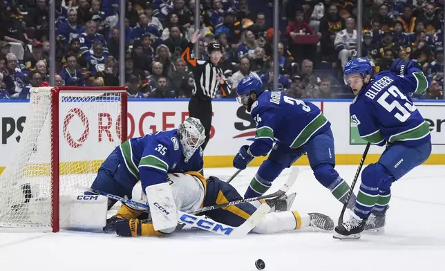 Nashville Predators' Jeremy Lauzon, bottom left, collides with Vancouver Canucks goalie Thatcher Demko (35) as Phillip Di Giuseppe (34) and Teddy Blueger (53) defend during the second period in Game 1 of an NHL hockey Stanley Cup first-round playoff series in Vancouver, British Columbia, on Sunday, April 21, 2024. (Darryl Dyck/The Canadian Press via AP)