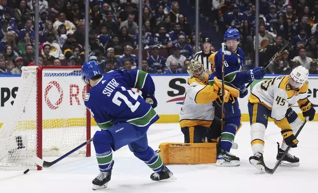 Vancouver Canucks' Pius Suter, left, misses the open net as Nashville Predators goalie Juuse Saros is tied up with Canucks' Brock Boeser during the third period in Game 2 of an NHL hockey Stanley Cup first-round playoff series Tuesday, April 23, 2024, in Vancouver, British Columbia. (Darryl Dyck/The Canadian Press via AP)