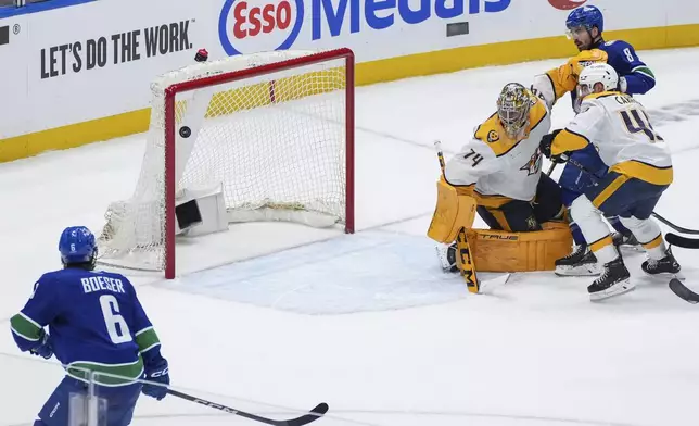 Vancouver Canucks' Brock Boeser (6) watches as his shot bounces off the post and stays out of the net behind Nashville Predators goalie Juuse Saros (74) while Alexandre Carrier (45) and Canucks' Conor Garland (8) watch during the second period in Game 2 of an NHL hockey Stanley Cup first-round playoff series Tuesday, April 23, 2024, in Vancouver, British Columbia. (Darryl Dyck/The Canadian Press via AP)