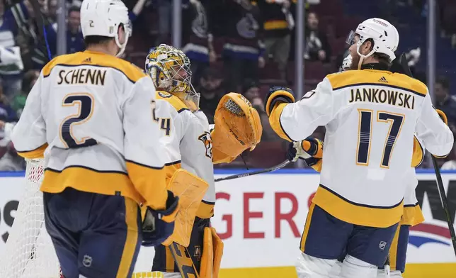 Nashville Predators goalie Juuse Saros, back left, Mark Jankowski (17) and Luke Schenn (2) celebrate after Nashville defeated the Vancouver Canucks during Game 2 of an NHL hockey Stanley Cup first-round playoff series Tuesday, April 23, 2024, in Vancouver, British Columbia. (Darryl Dyck/The Canadian Press via AP)
