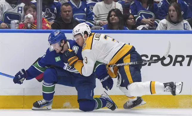 Nashville Predators' Jeremy Lauzon, right, checks Vancouver Canucks' Nils Hoglander during the third period in Game 2 of an NHL hockey Stanley Cup first-round playoff series Tuesday, April 23, 2024, in Vancouver, British Columbia. (Darryl Dyck/The Canadian Press via AP)