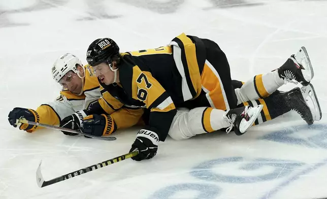 Pittsburgh Penguins' Rickard Rakell (67) lands on top of Nashville Predators' Cole Smith, left, during the third period of an NHL hockey game, Monday, April 15, 2024, in Pittsburgh. (AP Photo/Matt Freed)