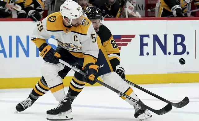 Nashville Predators' Roman Josi (59) and Pittsburgh Pittsburgh Penguins' Michael Bunting (8) fight for the puck during the second period of an NHL hockey game, Monday, April 15, 2024, in Pittsburgh. (AP Photo/Matt Freed)