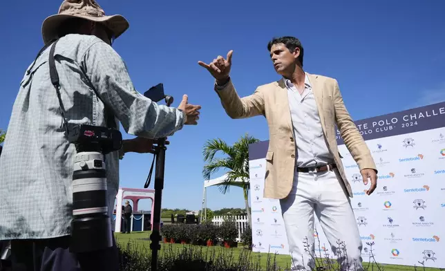 Argentine professional polo player Ignacio "Nacho" Figueras, right, greets journalists as he arrives for the 2024 Royal Salute Polo Challenge to Benefit Sentebale, Friday, April 12, 2024, in Wellington, Fla. Prince Harry, co-founding patron of the Sentebale charity, will play on the Royal Salute Sentebale Team. (AP Photo/Rebecca Blackwell)