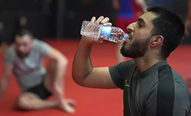 A student drinks water during a break at a mixed martial arts practice session at Diesel Gym in the Docklands area of East London, Monday, March 25, 2024. The special sessions run by the nonprofit SCK Fitness are held at 10 p.m. during the Muslim holy month of Ramadan to accommodate dawn-to-dusk fasting. (AP Photo/Kin Cheung)