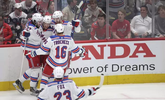New York Rangers left wing Artemi Panarin, center, celebrates with teammates after scoring a goal during the third period in Game 4 of an NHL hockey Stanley Cup first-round playoff series against the Washington Capitals, Sunday, April 28, 2024, in Washington. (AP Photo/Tom Brenner)