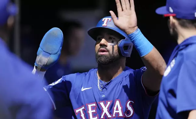 Texas Rangers designated hitter Ezequiel Duran is greeted in the dugout after scoring during the fifth inning of a baseball game against the Detroit Tigers, Tuesday, April 16, 2024, in Detroit. (AP Photo/Carlos Osorio)