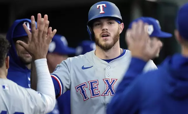 Texas Rangers' Jonah Heim is greeted in the dugout after scoring during the fifth inning of a baseball game against the Detroit Tigers, Monday, April 15, 2024, in Detroit. (AP Photo/Carlos Osorio)