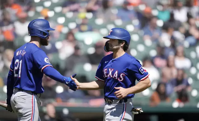 Texas Rangers' Josh Smith is greeted by Jared Walsh (21) after scoring from third on a single by designated hittere Ezequiel Duran during the fifth inning of a baseball game against the Detroit Tigers, Tuesday, April 16, 2024, in Detroit. (AP Photo/Carlos Osorio)