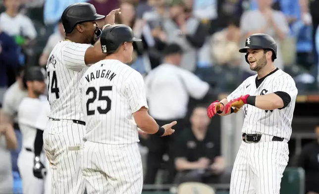 Chicago White Sox's Andrew Benintendi, right, is greeted at home plate by Eloy Jiménez, left, and Andrew Vaughn (25) after they scored on Benintendi's three-run home run off Tampa Bay Rays starting pitcher Aaron Civale during the fourth inning of a baseball game Saturday, April 27, 2024, in Chicago. (AP Photo/Charles Rex Arbogast)