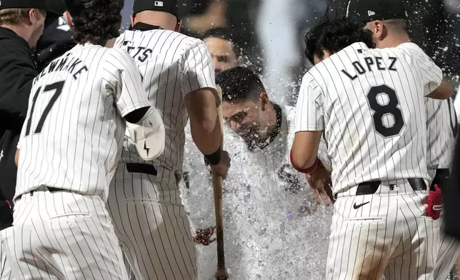 Chicago White Sox's Andrew Benintendi, center, celebrates with teammates after his winning two-run home run off Tampa Bay Rays relief pitcher Phil Maton to end a 10-inning baseball game Saturday, April 27, 2024, in Chicago. (AP Photo/Charles Rex Arbogast)