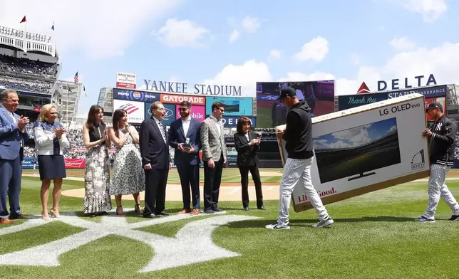 New York Yankees broadcaster John Sterling is presented with a television during retirement ceremony before a baseball game against the Tampa Bay Rays at Yankee Stadium in New York, Saturday, April 20, 2024 (AP Photo/Noah K. Murray)