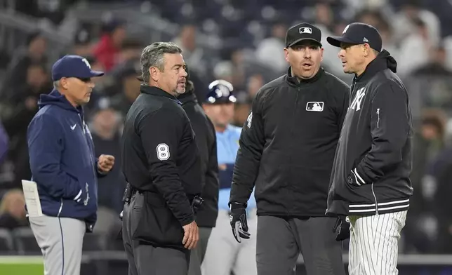 New York Yankees manager Aaron Boone, right, and Tampa Bay Rays manager Kevin Cash, left, talk to officials during the ninth inning of a baseball game Friday, April 19, 2024, in New York. (AP Photo/Frank Franklin II)