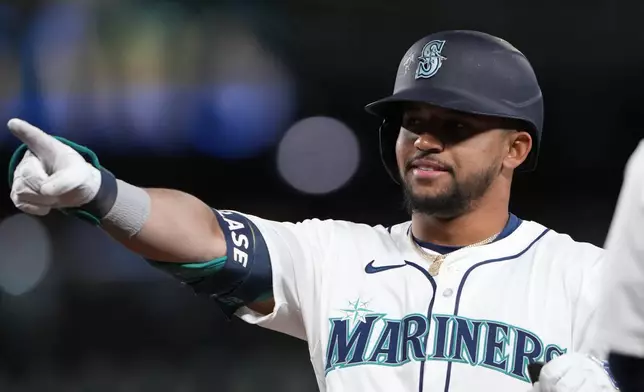 Seattle Mariners' Jonatan Clase points to the dugout after hitting an RBI single for his first major league hit against the Cincinnati Reds during the sixth inning of a baseball game Monday, April 15, 2024, in Seattle. (AP Photo/Lindsey Wasson)