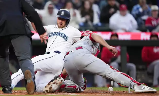 Seattle Mariners' Mitch Garver slides home to score on a double by Jonatan Clase, while Cincinnati Reds catcher Luke Maile drops the ball during the fourth inning of a baseball game Tuesday, April 16, 2024, in Seattle. (AP Photo/Lindsey Wasson)