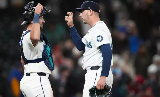 Seattle Mariners catcher Cal Raleigh, left, greets relief pitcher Tayler Saucedo after the team's win over the Cincinnati Reds in a baseball game Tuesday, April 16, 2024, in Seattle. (AP Photo/Lindsey Wasson)