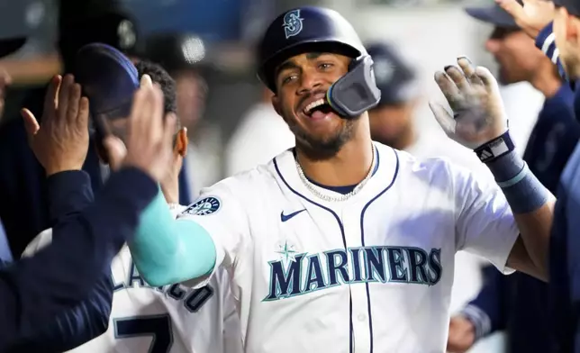 Seattle Mariners' Julio Rodríguez celebrates in the dugout after scoring on a bases-loaded walk during the fifth inning of the team's baseball game against the Cincinnati Reds on Tuesday, April 16, 2024, in Seattle. (AP Photo/Lindsey Wasson)