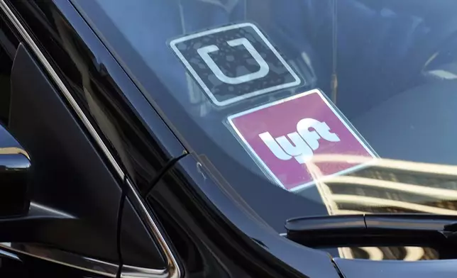 FILE - In this Jan. 12, 2016, file photo, a ride share car displays Lyft and Uber stickers on its front windshield in downtown Los Angeles. The future of Uber and Lyft in Minneapolis has been a source of concern and debate in recent weeks after the City Council voted last month to require that ride-hailing companies pay drivers a higher rate while they are within city limits. (AP Photo/Richard Vogel, File)