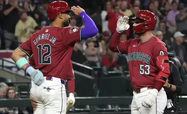 Arizona Diamondbacks' Christian Walker (53) celebrates with Lourdes Gurriel Jr. after hitting a two-run home run against the Colorado Rockies during the first inning of a baseball game Sunday, March 31, 2024, in Phoenix. (AP Photo/Rick Scuteri)