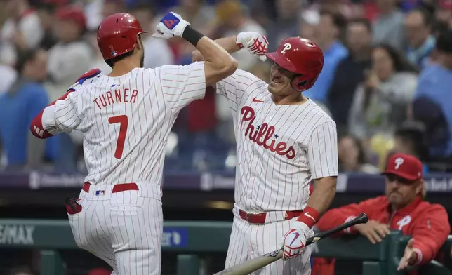 Philadelphia Phillies' Trea Turner (7) celebrates his home run off Colorado Rockies pitcher Ryan Feltner with J.T. Realmuto during the first inning of a baseball game Wednesday, April 17, 2024, in Philadelphia. (AP Photo/Matt Rourke)