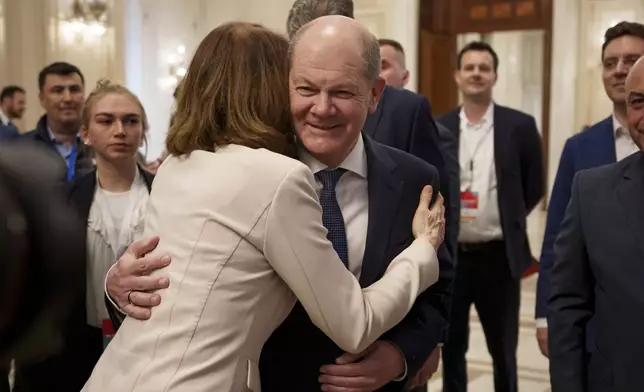 Katarina Barley, left, hugs German Chancellor Olaf Scholz, center, as they arrive at the Party of European Socialists (PES) Leaders Conference, at the Palace of the Parliament, the second largest administrative building in the world after the Pentagon, in Bucharest, Romania, Saturday, April 6, 2024. (AP Photo/Andreea Alexandru)