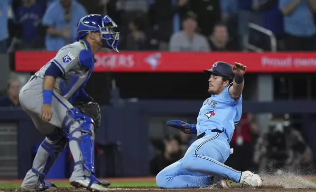 Toronto Blue Jays' Addison Barger, right, slides past Kansas City Royals catcher Freddy Fermin, left, to score during sixth -inning baseball game action in Toronto, Monday, April 29, 2024. (Nathan Denette/The Canadian Press via AP)
