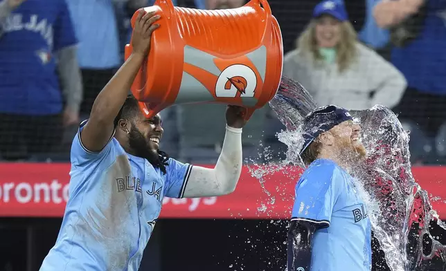 Toronto Blue Jays first baseman Vladimir Guerrero Jr., left, dumps water on Blue Jays designated Hitter Justin Turner, right, after they defeated the Kansas City Royals in baseball game action in Toronto, Monday, April 29, 2024. (Nathan Denette/The Canadian Press via AP)