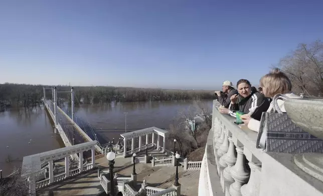 Local residents stay on a pedestrian bridge crossing the overflowing Ural River in Orenburg, Russia, on Thursday, April 11, 2024. Russian officials are scrambling to help homeowners displaced by floods, as water levels have risen in the Ural River. The river's water level in the city of Orenburg was above 10 meters (33 feet) Wednesday, state news agency Ria Novosti reported, citing the regional governor. (AP Photo)