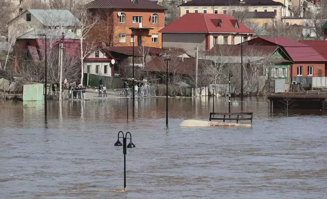 Local residents stand at a barriers watching a flooded area in Orenburg, Russia, on Thursday, April 11, 2024. Russian officials are scrambling to help homeowners displaced by floods, as water levels have risen in the Ural River. The river's water level in the city of Orenburg was above 10 meters (33 feet) Wednesday, state news agency Ria Novosti reported, citing the regional governor. (AP Photo)
