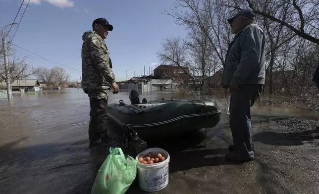 Two local residents are going ride a rubber boat to leave a flooded area in Orenburg, Russia, on Thursday, April 11, 2024. Russian officials are scrambling to help homeowners displaced by floods, as water levels have risen in the Ural River. The river's water level in the city of Orenburg was above 10 meters (33 feet) Wednesday, state news agency Ria Novosti reported, citing the regional governor. (AP Photo)