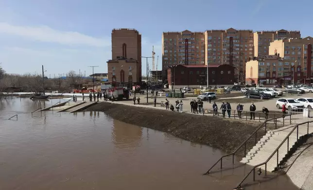 Local residents watch a flooded area in Orenburg, Russia, on Thursday, April 11, 2024. Russian officials are scrambling to help homeowners displaced by floods, as water levels have risen in the Ural River. The river's water level in the city of Orenburg was above 10 meters (33 feet) Wednesday, state news agency Ria Novosti reported, citing the regional governor. (AP Photo)